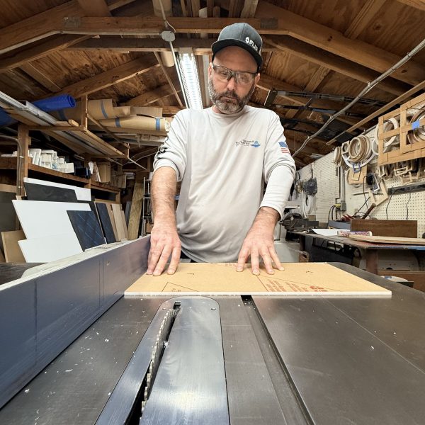 Electronics Unlimited carpenter cutting a panel on a table saw in the in-house carpentry shop