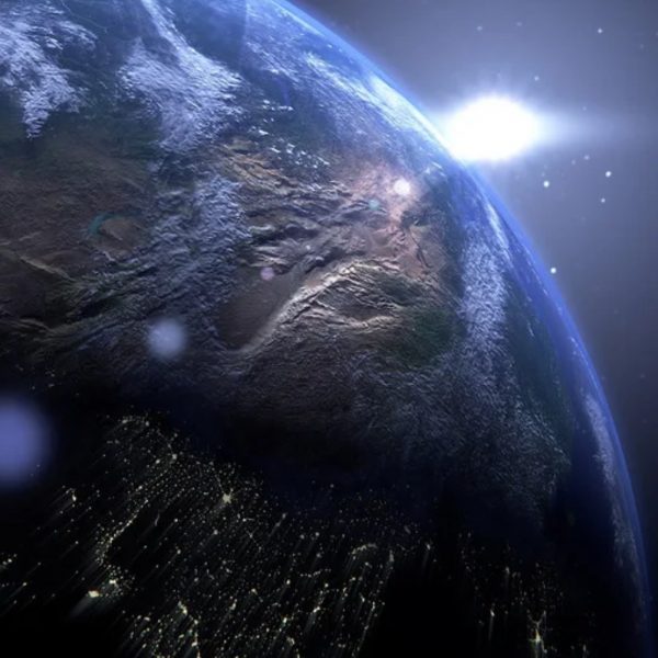 Earth from orbit at sunrise with city lights across the night side