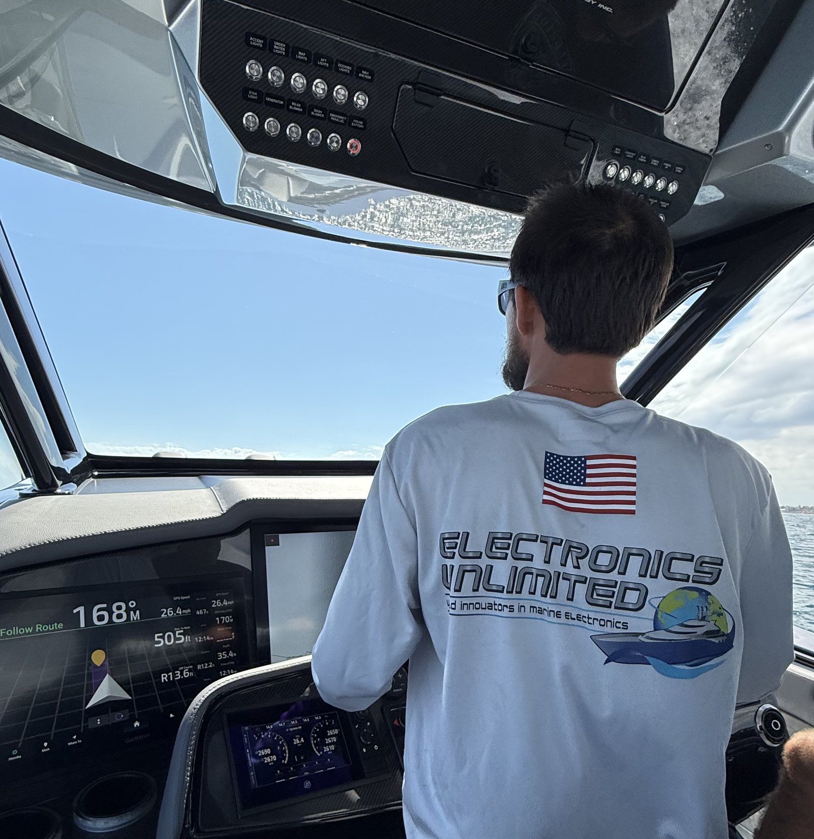 Electronics Unlimited technician at the helm of a performance boat underway